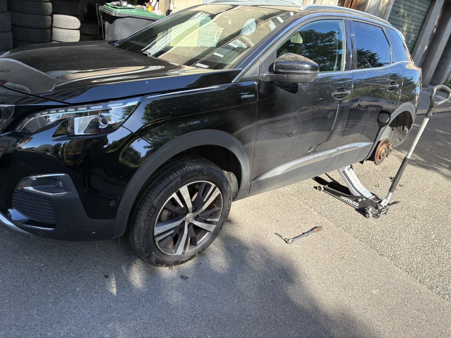 Wechsel eines defekten Reifens an einem aufgebockten Peugeot 3008, Hinterrad demontiert, während eines Vaudauto-Einsatzes in Lausanne